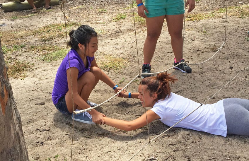 Photo: Camp participants help a girl through an obstacle